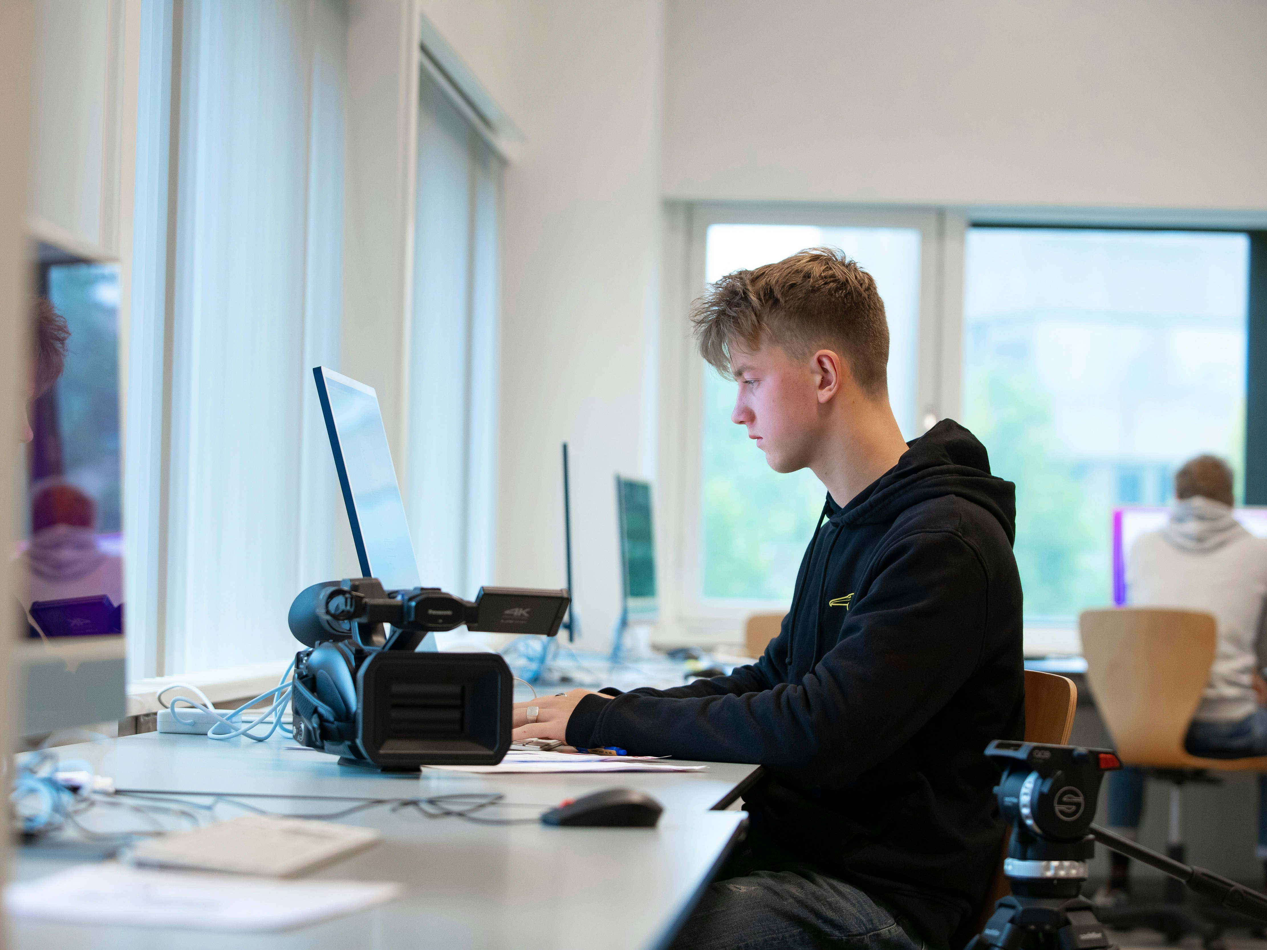 Student achter laptop met een camera op de tafel